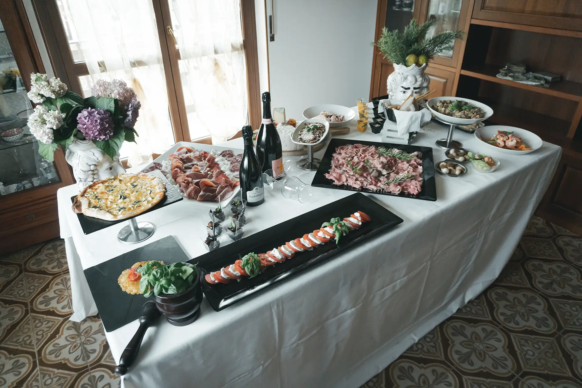 Presentazione di catering con torta salata, affettati, caprese, gamberi, parmigiana ed altri piatti
